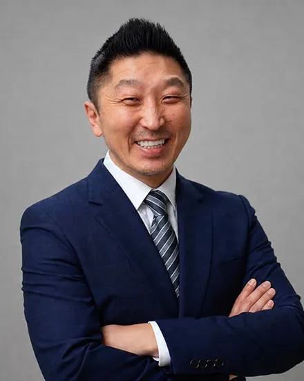 Dr. Charles Lee, DDS, of Hybrid Dental, smiling in a navy suit