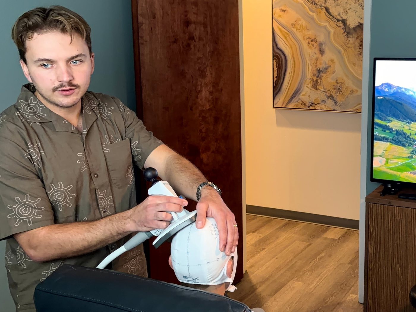 A clinician holds the TMS coil in place during a session