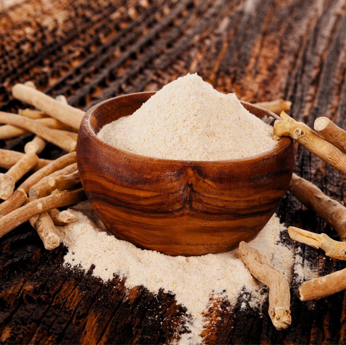 Dried roots and powdered root in a wooden bowl