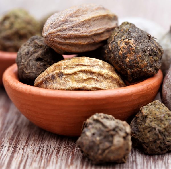 Whole triphala fruits in a clay bowl